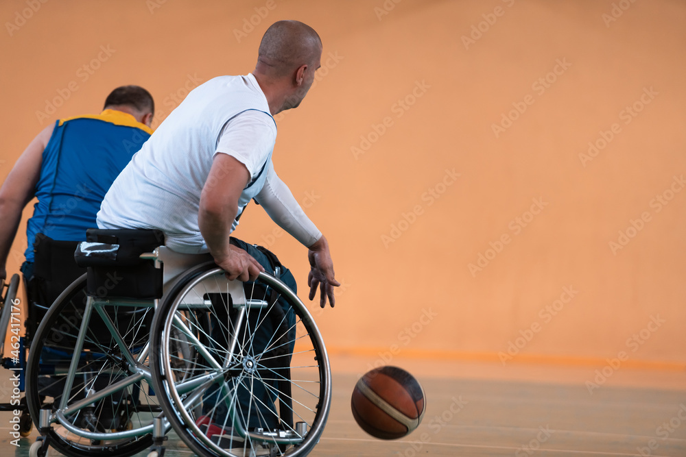 Disabled War veterans mixed race and age basketball teams in wheelchairs playing a training match in a sports gym hall. Handicapped people rehabilitation and inclusion concept Disabled War veterans mixed race and age basketball teams in wheelchairs playing a training match in a sports gym hall. Handicapped people rehabilitation and inclusion concept