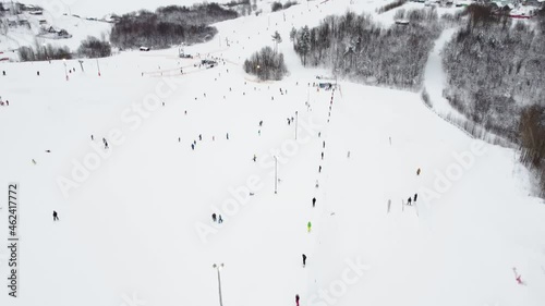 Panoramic top view from drone on cable way in ski resort. Ski lift elevator transporting skiers and snowboarders on snowy winter slope at mountain resort, many people. UHD 4k video