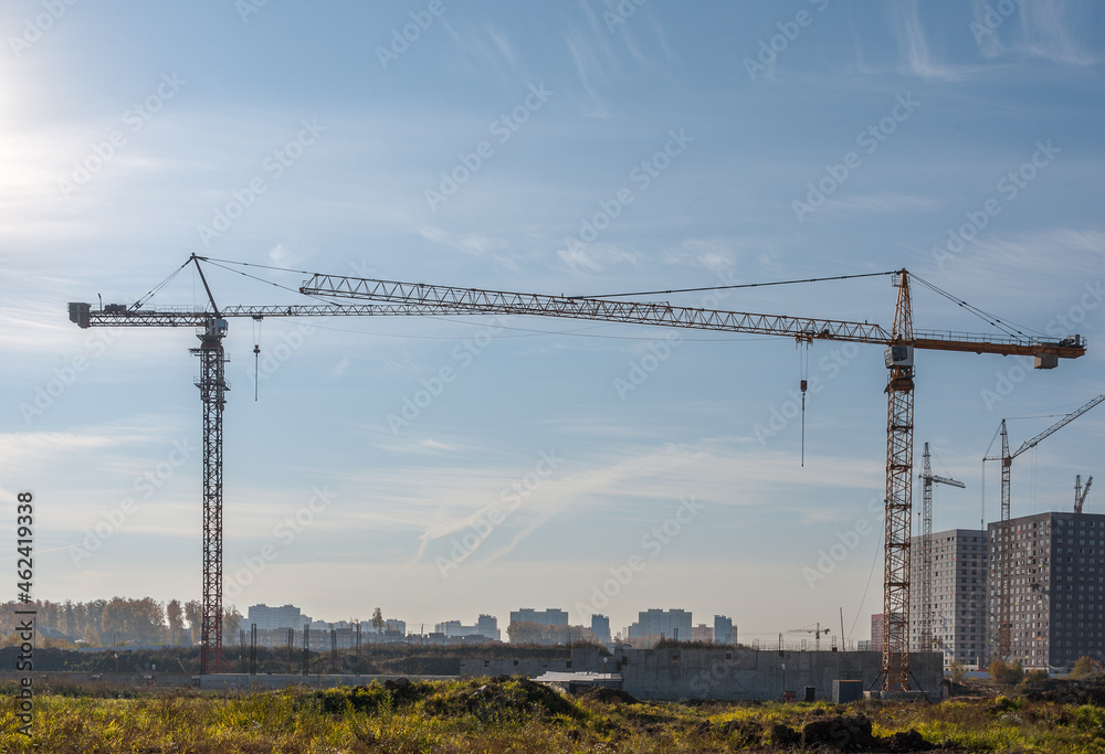 There are construction cranes on the construction site that stand opposite each other