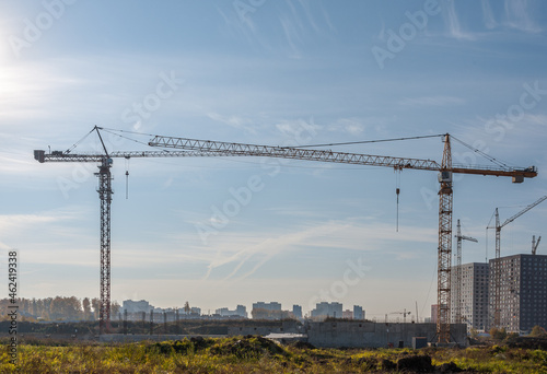 There are construction cranes on the construction site that stand opposite each other