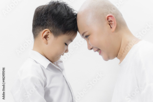 Young adult female cancer patient spending time with son at home, relaxing on the couch. Cancer and family support concept.