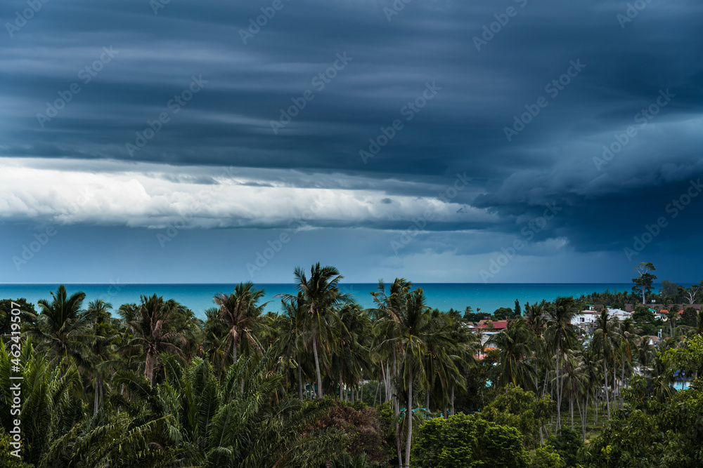 Dramatic storm clouds over the sea, forest and rooftops on a summer day Dramatic storm clouds over the sea, forest and rooftops on a summer day
