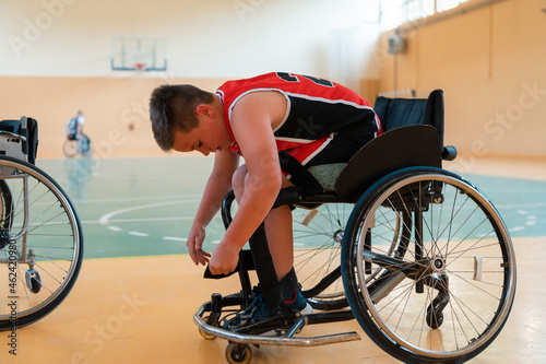 the boy sits in a wheelchair and prepares for the basketball start of the game in the big arena