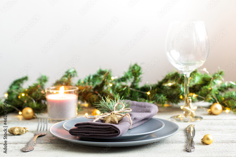table setting for Christmas dinner with decorations on grey plate on white table. Holiday view with christmas tree.