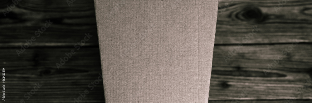 Fototapeta premium mockup empty craft trapezoidal cardboard box on an old wooden table close up. tinted in black color. top view, flat lay and space for text. banner
