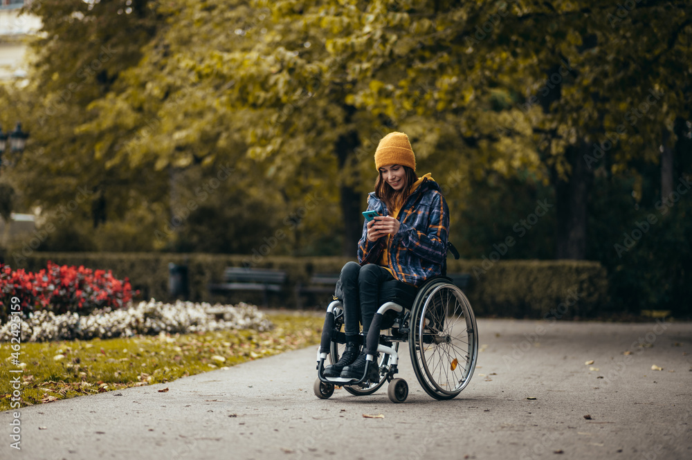 Woman in wheelchair using a smartphone while out in the city park
