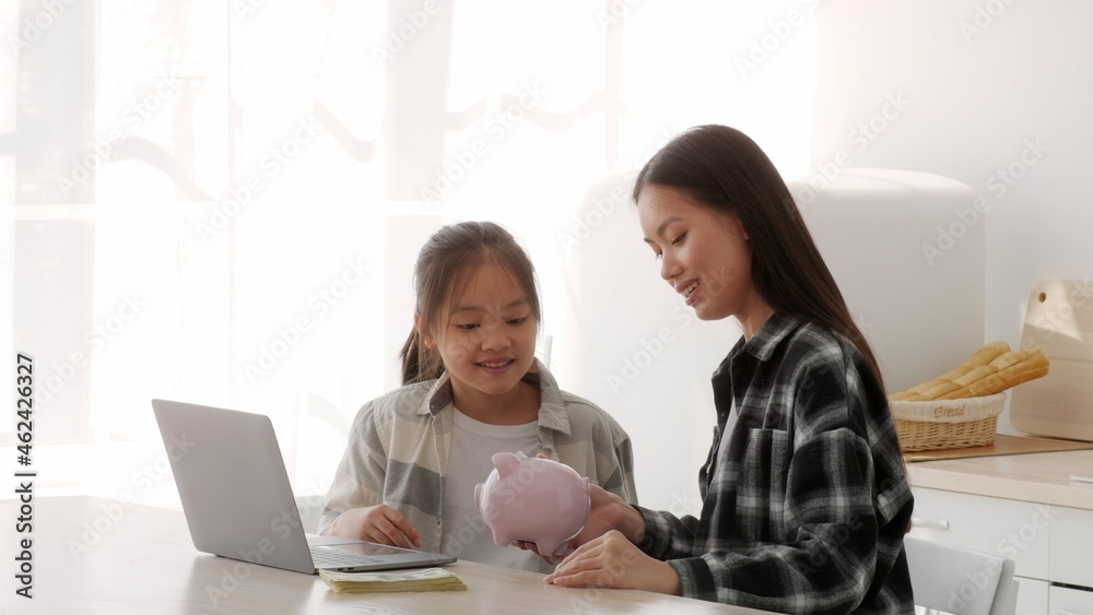 Asian Mother And Daughter Putting Money Coin In Piggybank Indoor Asian Mother And Daughter Putting Money Coin In Piggybank Indoor