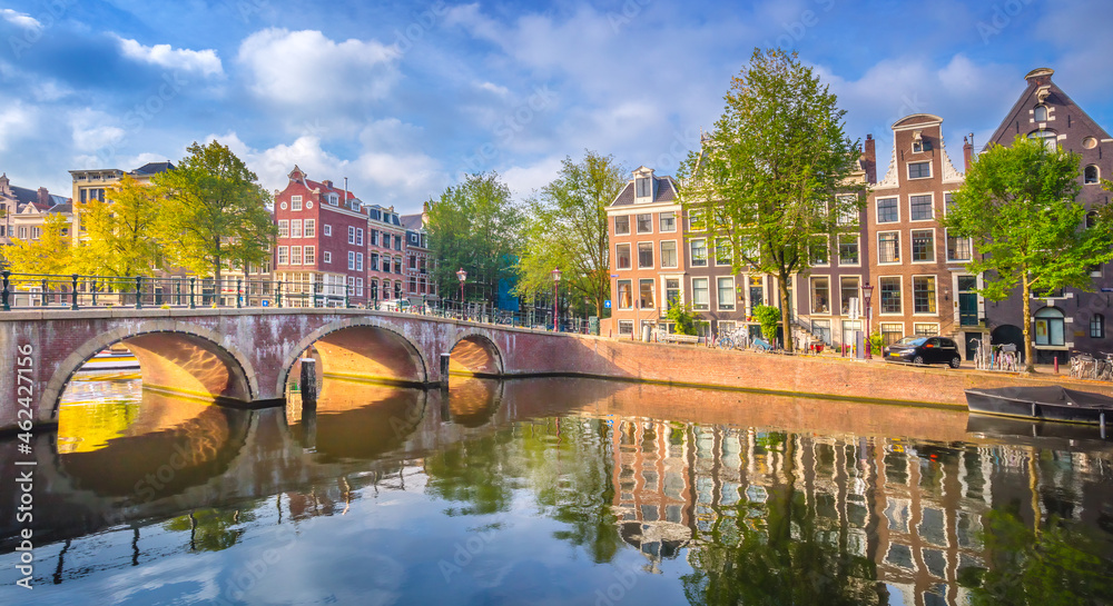 Amsterdam. Panoramic view of the historic city center of Amsterdam. Traditional houses and bridges of Amsterdam. An early quiet morning and the serene reflection of houses in the water. 