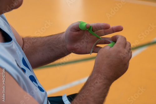 a disabled basketball player puts on a corset and bandages on his arms and fingers in preparation for a game in the arena