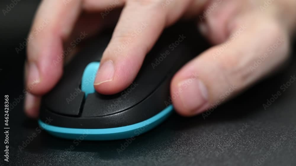 A man is playing games using a bluetooth Logitech mouse. A man is playing games using a bluetooth Logitech mouse.