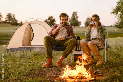 White couple smiling and drinking tea during camping together photo