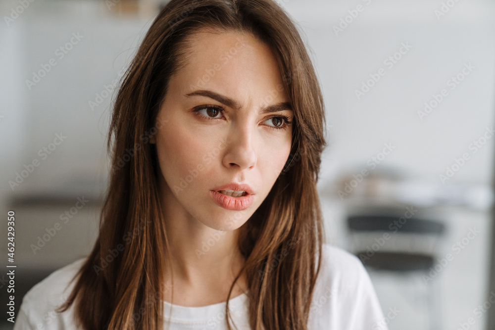 Young white woman frowning and looking aside indoors