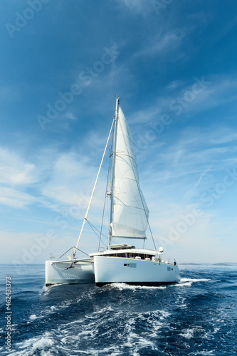 Fotografia Luxury catamaran sailing under white sails on the blue azure sea on a sunny summer day