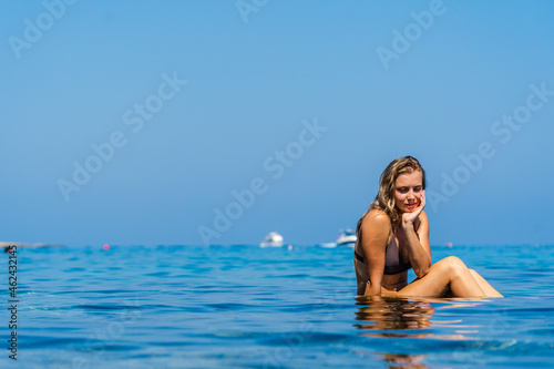 Beautiful woman sits on stone around the clear water of the Sea © Anton Tolmachov