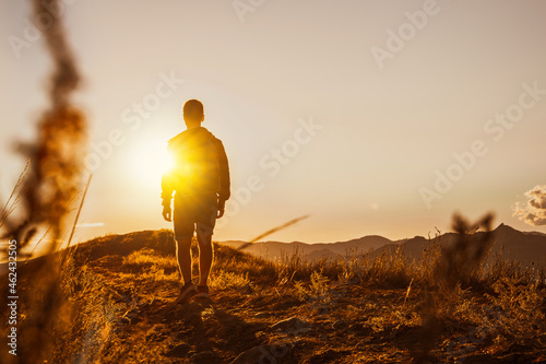 Male silhouette at sunset on a mountain top. Sport travel and active life concept. Beauty world.