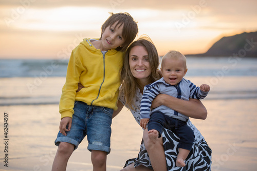 Young mother with her beautiful children, enjoying the sunset over the ocean on a low tide in Devon
