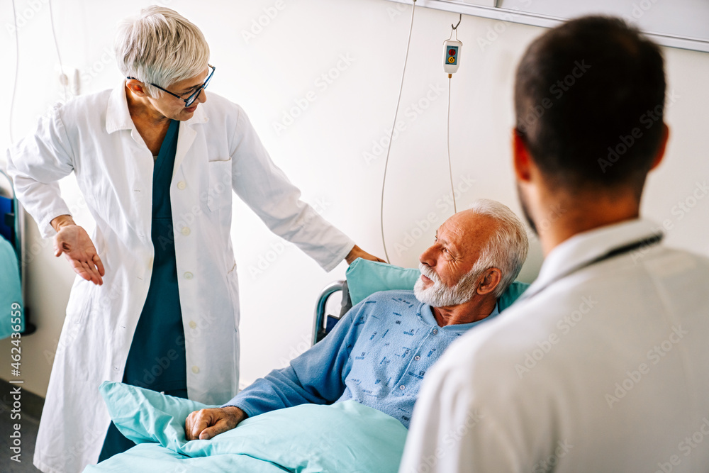 Obraz premium Doctor consulting happy senior man patient on hospital bed. Healthcare and medical insurance concept
