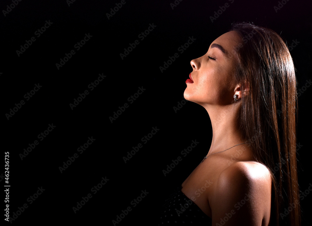 beautiful young woman with luxurious makeup and bare shoulders. Black background with space for text beautiful young woman with luxurious makeup and bare shoulders. Black background with space for text