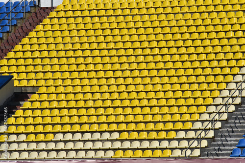 lots of rows with yellow seats for people on the football field in the summer