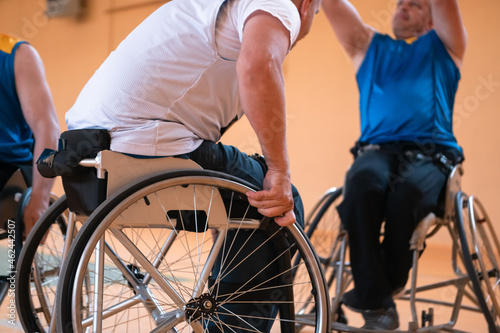 Close up photo of wheelchairs and handicapped war veterans playing basketball on the court