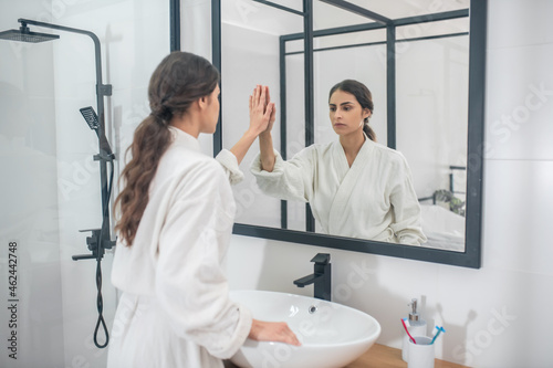 A dark-haired young girl in a white bathrobe in the bathroom