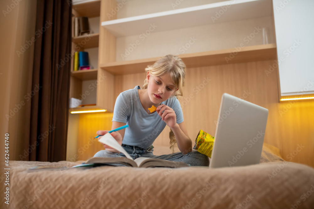 A teen girl lying on the bed and doing her lessons A teen girl lying on the bed and doing her lessons