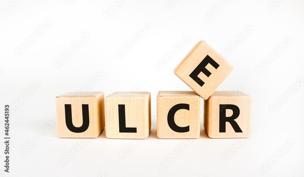 Stomach ulcer symbol. Wooden cubes with the word 'ulcer'. Beautiful white table, white background. Medical and stomach ulcer concept. Copy space. Stomach ulcer symbol. Wooden cubes with the word 'ulcer'. Beautiful white table, white background. Medical and stomach ulcer concept. Copy space.