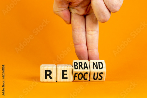 Refocus and rebrand symbol. Businessman turns cubes and changes the word 'refocus' to 'rebrand'. Beautiful orange table, orange background. Business, refocus and rebrand concept. Copy space. photo