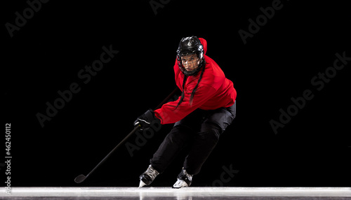 Full-length portrait of professional female hockey player training isolated over black background. Stickhandling