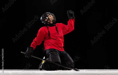 Photography Portrait of professional female hockey player in special protective helmet isolated over black background