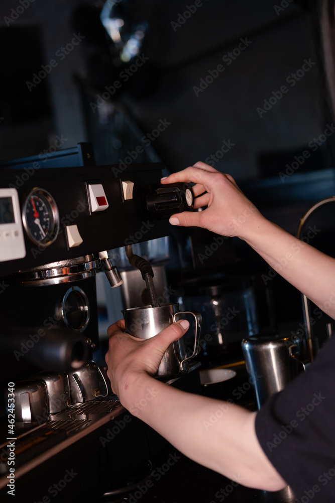 Process of preparing milk foam for cappuccino or latte, heating and whipping. Barista steaming milk in the pitcher