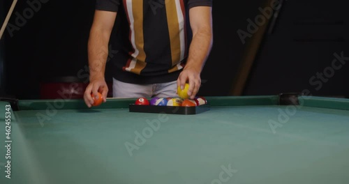 Young man are going to play billiards, folding balls into a triangle photo