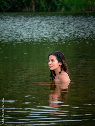 Fototapeta Naklejka Na Ścianę i Meble -  Latin Woman with a Suspicious Look is Swimming in the San Salvador River Surrounded by Vegetation in Palomino, La Guajira, Colombia