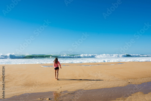 pretty little girl barefoot by the turquoise ocean