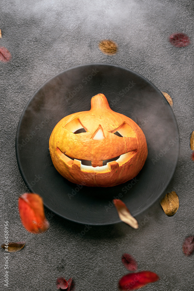 a scary orange pumpkin on the table, glowing eyes, a black plate and a background. halloween party invitation to a restaurant or to a celebration in a bar card a scary orange pumpkin on the table, glowing eyes, a black plate and a background. halloween party invitation to a restaurant or to a celebration in a bar card