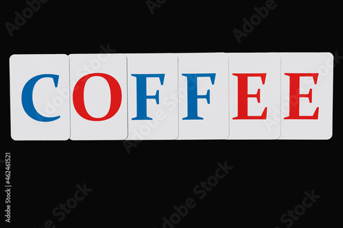 The word coffee made up of letters of blue and red color on white cards laid out in a line on a black background