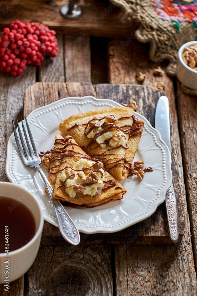 Pancakes with walnuts, chocolate and mascarpone cream. Wooden background, side view. Rowan Pancakes with walnuts, chocolate and mascarpone cream. Wooden background, side view. Rowan