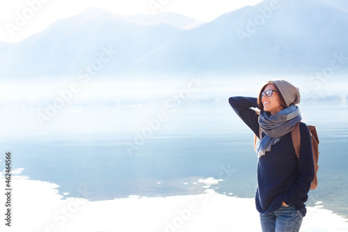 Young woman traveling by winter sea beach. Traveler enjoying back to normal trip