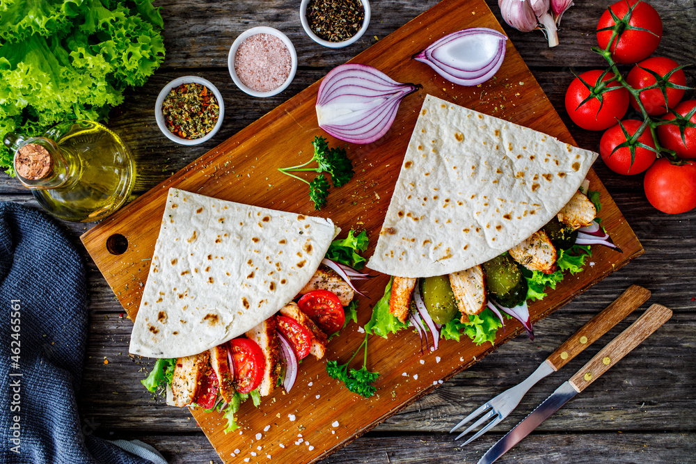 Italian piada wraps - piadina stuffed with fresh vegetables and roast chicken breast  on wooden table
 - obrazy, fototapety, plakaty 