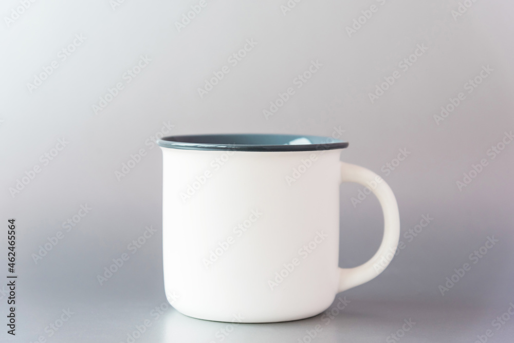 New white blank template metal mug with big handle for drinks reflected on shining surface stands on light grey background, copy space, mockup New white blank template metal mug with big handle for drinks reflected on shining surface stands on light grey background, copy space, mockup