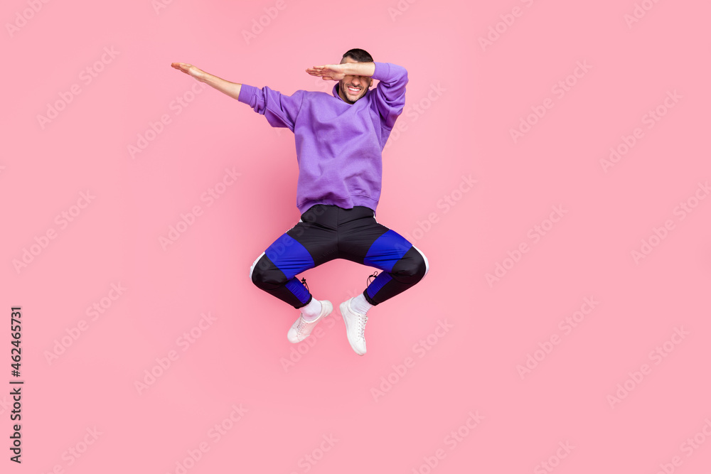 Full body photo of young excited man dance dab cover eyes hands jump up isolated over pink color background