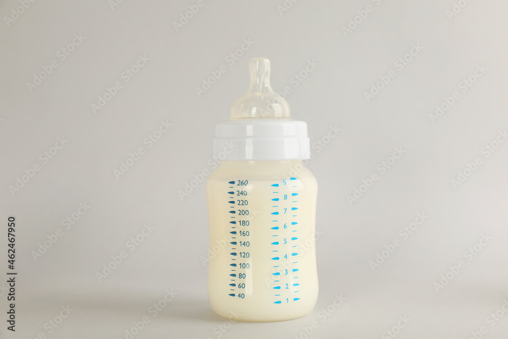 Feeding bottle with infant formula on light grey background. Baby milk Feeding bottle with infant formula on light grey background. Baby milk