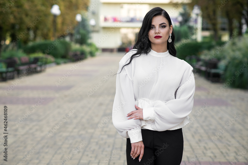 Fototapeta premium Portrait of a beautiful, young and attractive Caucasian brunette girl. Elegant girl posing in the summer in the park. Fashion concept.