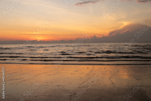 The golden-orange sunlight hits the sea and sand.