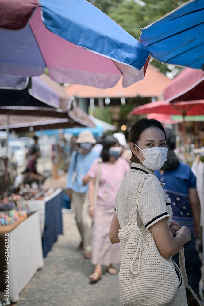 Young women wear surgical protection mask and carrying reusable bag walking in street market