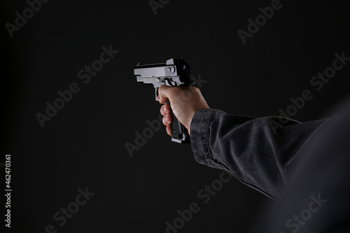 Man holding gun on black background, closeup