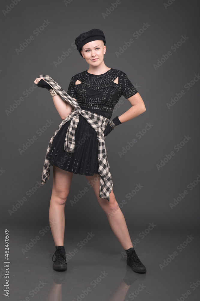 Young, Fashionable Woman Poses Before a Plain Grey Background Young, Fashionable Woman Poses Before a Plain Grey Background