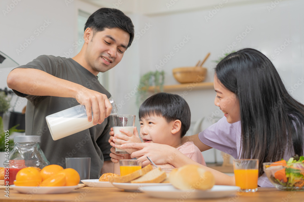Happy refreshment family breakfast in morning, asian young parent father, mother and little boy having meal, pouring milk to child in kitchen eating together at home. Cheerful, enjoy cooking people. Happy refreshment family breakfast in morning, asian young parent father, mother and little boy having meal, pouring milk to child in kitchen eating together at home. Cheerful, enjoy cooking people.