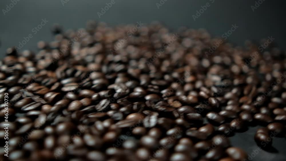 Pile of roasted coffee beans moving on black surface Pile of roasted coffee beans moving on black surface