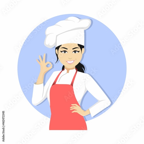 Confident young Asian female chef in uniform winks one eye and gestures with her hand